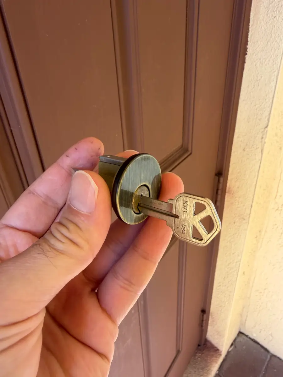 Landlord Rekeying Guide West Memphis AR: Key Control Tips 1 Locksmith holding rekeyed Kwikset lock cylinder with new key during rental property rekeying service in West Memphis AR