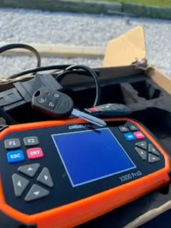 Car Key Replacement Rogers AR: 2026 Cost Guide by Key Type 3 Key programmer with freshly cut car keys and remote fob on a mobile locksmith job in Northwest Arkansas